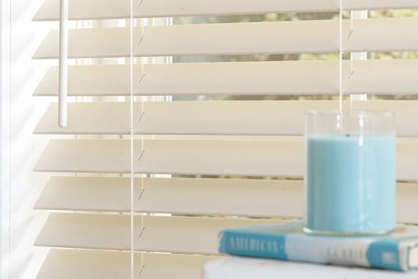 Close up on clean blinds with a complimentary blue candle and book.