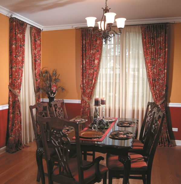 Traditional floral draperies paired with sheer curtains in a family dining room.