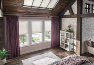 Cozy nook with rustic decor off a living room area with a set of three windows adored by cellular shades and flanked by mauve-colored, floor-length drapes
